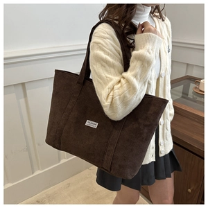 Detail of dark brown corduroy tote bag showing soft ribbed texture and fashion label