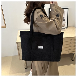 Detail of black corduroy tote bag with Fashion Instinct label on the front side