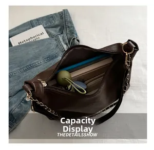 Vue détaillée de l'intérieur spacieux et de la chaîne dorée du sac en cuir marron