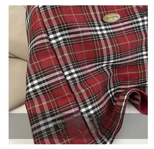 Detail of red plaid fabric with an oval handmade metal tag on a large canvas tote bag