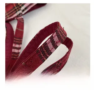 Detailed close-up of a red and black plaid tote bag strap with reinforced stitching