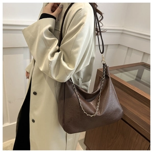 Mannequin portant un sac besace café foncé texture vintage avec détail de chaîne