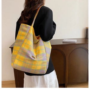 Detail of a large yellow plaid canvas tote bag worn by model showing its capacity