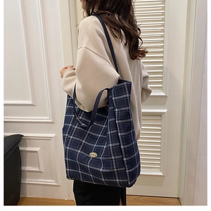 Detail view of blue and white plaid tote bag with side metal plate and canvas texture