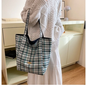 Detail view of large plaid tote bag featuring handmade label and heavy canvas texture