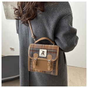 Détail d'un sac à main vintage à carreaux marron avec broderie ours et finitions cuir