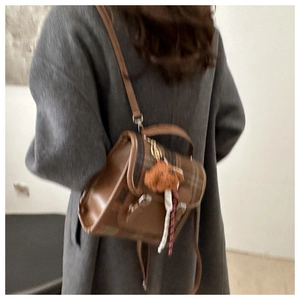 Detail shot of a vintage brown plaid mini backpack with a cute plush bear charm