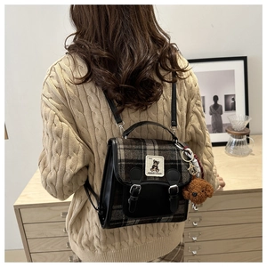 Detail view of British style checkered backpack with leather trim and plush charm