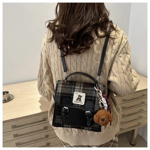 Detail of vintage plaid wool backpack with leather flap and cute plush puppy charm