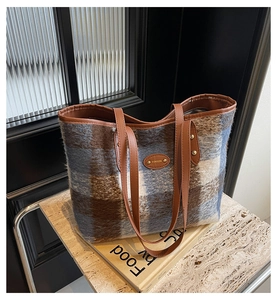 Close-up of wool plaid tote bag with brown leather handles and fuzzy fabric texture