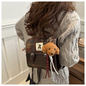 Detail of vintage plaid backpack with leather trim and cute plush teddy charm