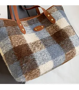 Detailed view of winter tote bag featuring plaid fabric texture and leather logo tag