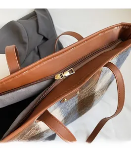 Detail of high-quality golden zipper and brown leather trim on plaid wool tote bag