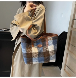 Model showing contrast tweed plaid tote bag with brown leather straps and metal buckle