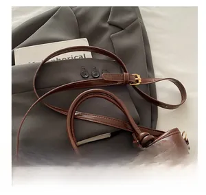 Detail of adjustable shoulder strap and knotted handles on brown leather bucket bag
