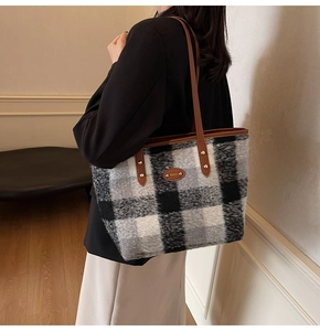 Detail of plaid wool tote bag showing leather shoulder straps and vintage autumn texture