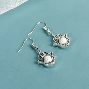 Vintage Hamsa Hand earrings with natural white turquoise stones on a blue background