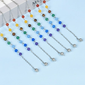 Set of seven colorful crystal bead chains with hollow silver sphere pendants on blue background
