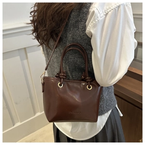 Deep brown vintage leather handbag with knotted handle and FASHION engraving on model