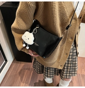 Dettaglio di una borsa a secchiello nera in pelle PU con un ciondolo a nuvola bianca