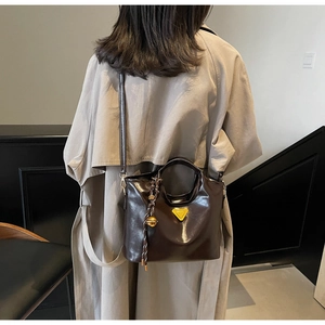 Détail du sac à main marron foncé en cuir verni brillant avec accent triangle jaune