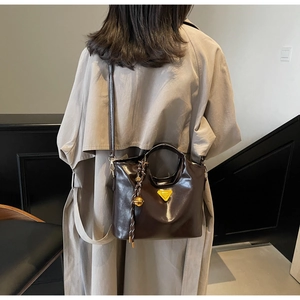 Détail du sac cabas en cuir brillant marron foncé avec logo triangulaire jaune design