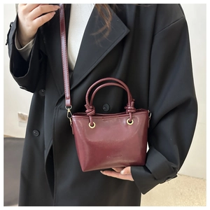 Detail of burgundy leather mini tote with gold hardware and stylish cylindrical handles