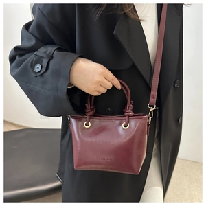 Détail du sac seau bordeaux en cuir synthétique avec logo embossé et finitions dorées