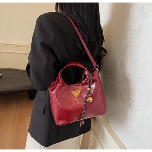 Détail de la texture en cuir rouge brillant et du pendentif tressé sur ce sac cabas chic
