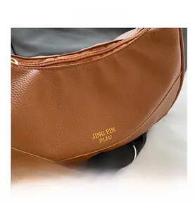 Detail of brown litchi pattern leather bag with golden logo and metal zipper