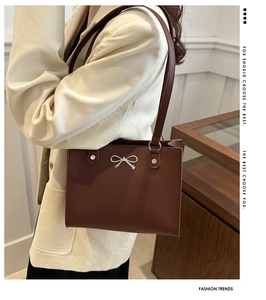 Brown faux leather shoulder bag with silver butterfly buckle shown in a lifestyle setting
