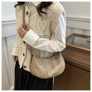 Macro detail of creamy faux leather texture and gold buckle on a stylish crescent bag