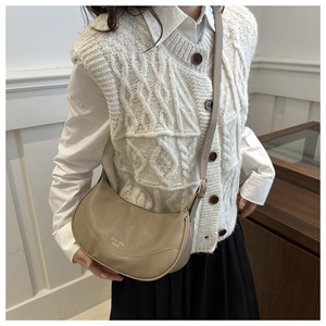 Detail view of khaki pebbled leather half-moon bag worn with a casual outfit