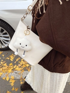Borsa a secchiello bianca con ciondolo a nuvola di peluche in un ambiente autunnale