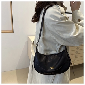 Detailed view of black lychee grain leather hobo bag worn with a beige trench coat