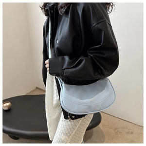 Detailed side view of a light blue crescent shoulder bag with pebbled leather texture