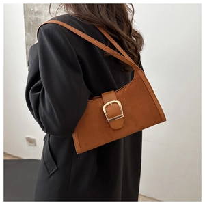 Detail view of brown suede underarm bag with large gold buckle on black blazer