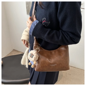 Brown vintage half-moon leather bag on model with cute sheep pendant detail
