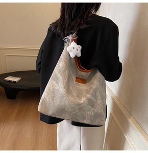 Gros plan d'un sac cabas en toile grise avec finitions en cuir et charm étoile peluche