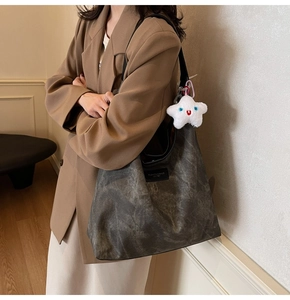 Détail du sac hobo gris vintage avec étiquette cuir et pendentif étoile en peluche blanche