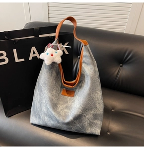 Détail du sac cabas en denim bleu avec anses en cuir marron et breloque étoile peluche