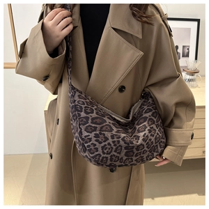 Close-up of leopard print canvas crossbody bag with wide strap on khaki coat