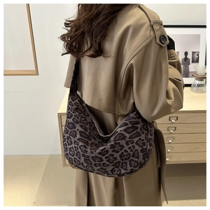 Leopard print hobo bag worn with a khaki trench coat in a stylish indoor setting