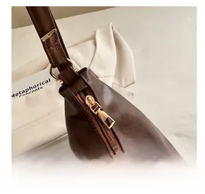 Detailed close-up of smooth golden metal zipper and brown PU leather texture on tote bag