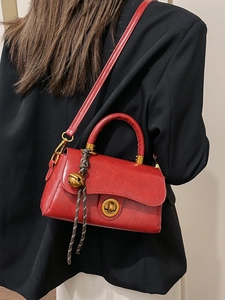 Rote Retro-Lederhandtasche mit goldenem Schloss und geflochtenem Anhänger am Modell
