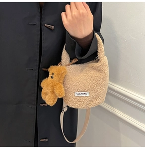 Détail du sac seau en polaire beige avec breloque ours sur un manteau noir