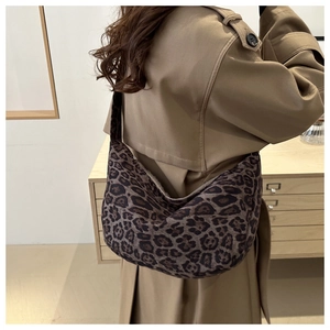 Close-up of stylish leopard print crescent tote bag worn with a neutral trench coat