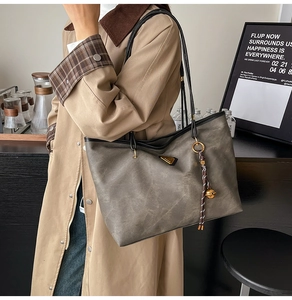 Détail d'un grand cabas vintage gris avec boucle métallique et breloque sur mannequin