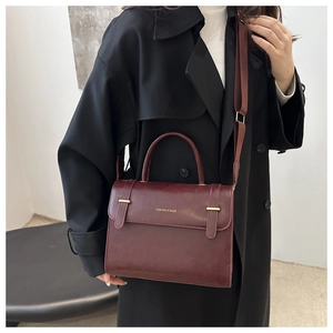 Détail du sac bandoulière bordeaux avec lettrage doré et bandoulière en tissu réglable