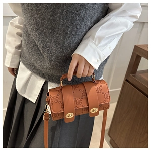 Detail of vintage brown cylinder bag featuring floral embossing and gold dual turn-locks